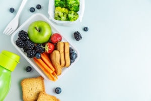 Healthy lunch to go. Fruits and vegetables packed in lunch box. Healthy eating concept. View from above with copy space.