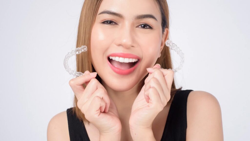 Young-smiling-woman-holding-invisalign-braces